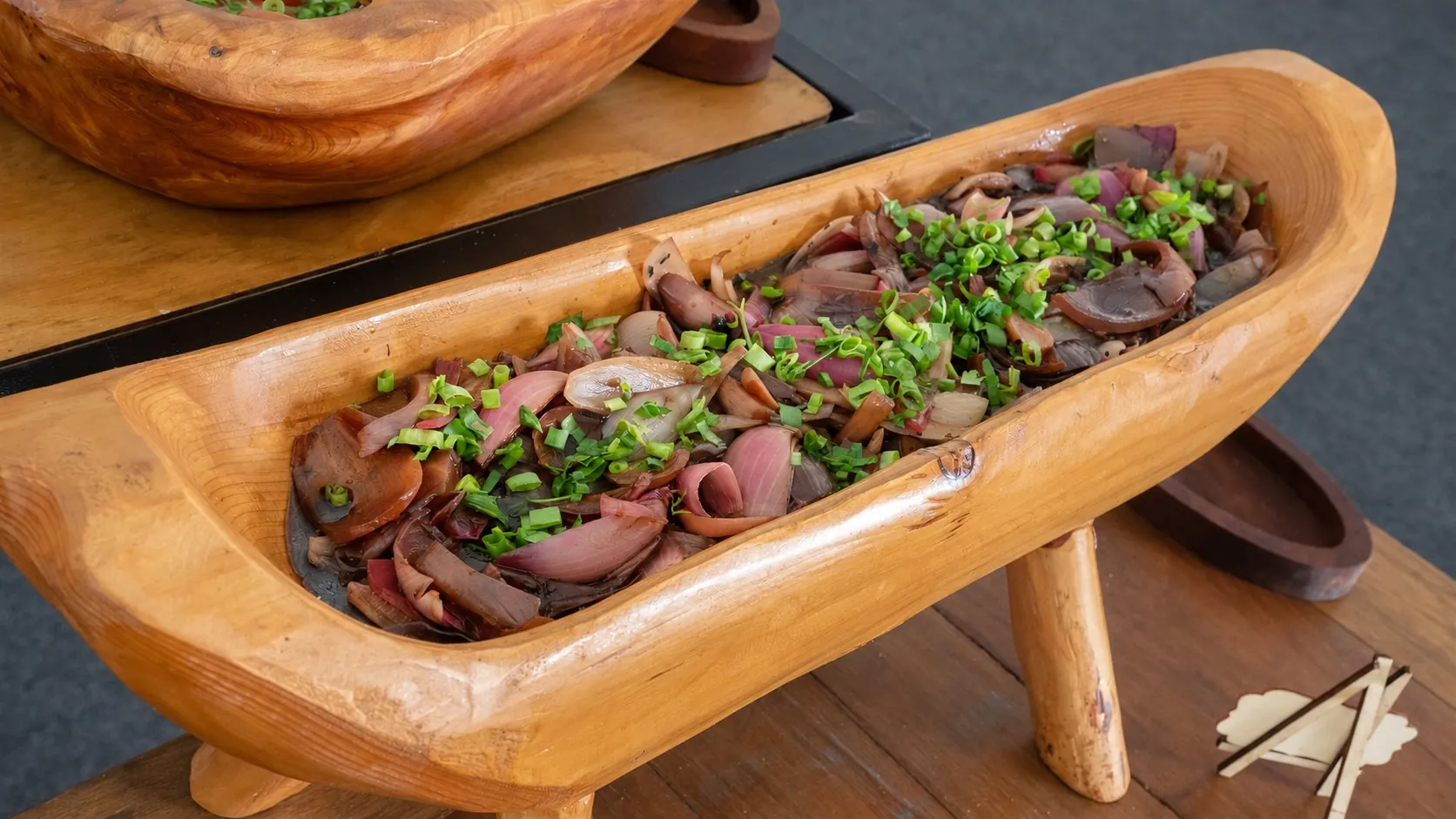 Cebolas preparadas com ervas e servidas em uma travessa de madeira