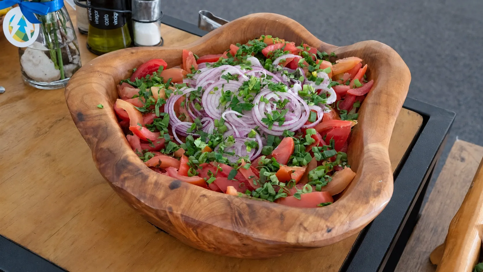 Salada de tomates, cebola-roxa e ervas frescas em uma tigela de madeira