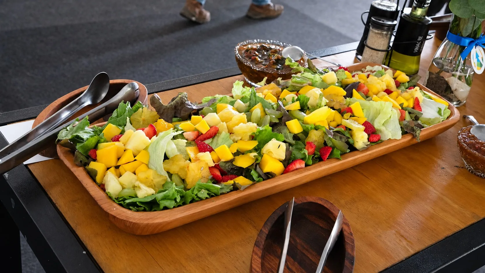 Salada tropical com folhas e frutas apresentada em uma travessa de madeira